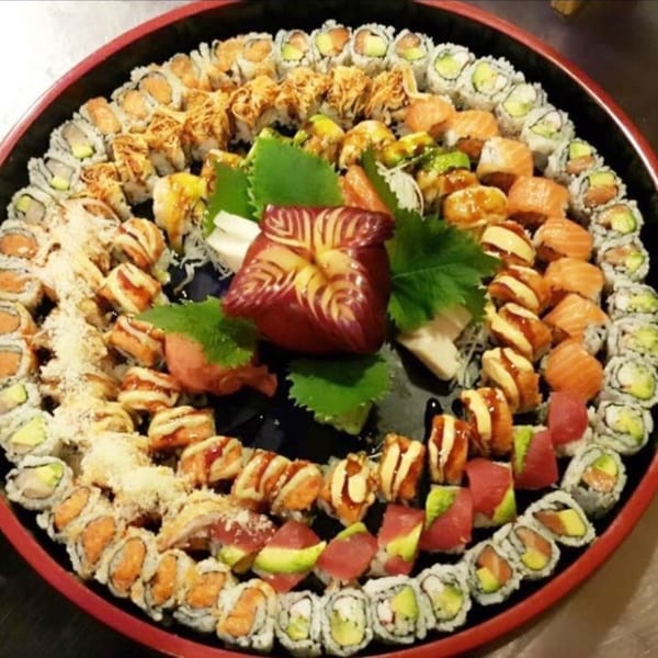 A large, round platter filled with various Elite Five Sushi & Grill sushi rolls and sashimi.