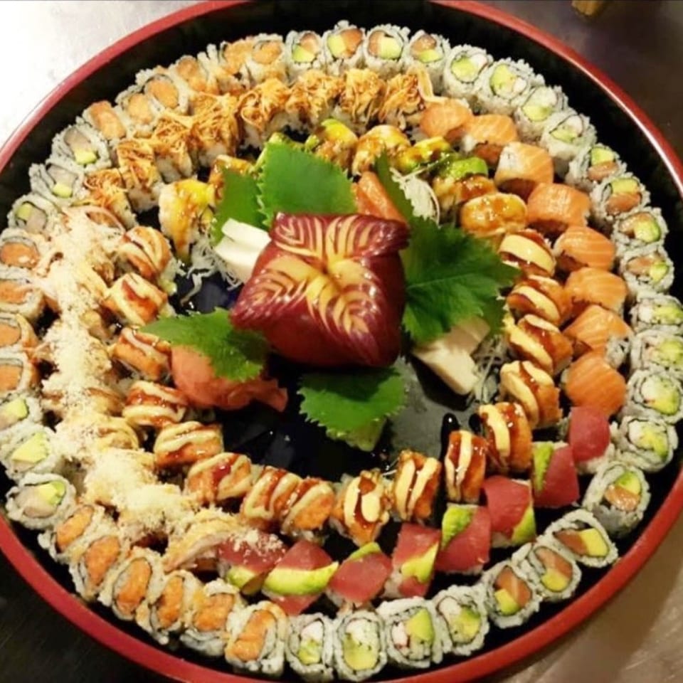 A large, round platter filled with various Elite Five Sushi & Grill sushi rolls and sashimi.