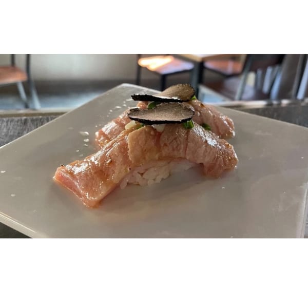 Two pieces of Elite Five Sushi & Grill's nigiri, topped with seared salmon and black truffle slices.